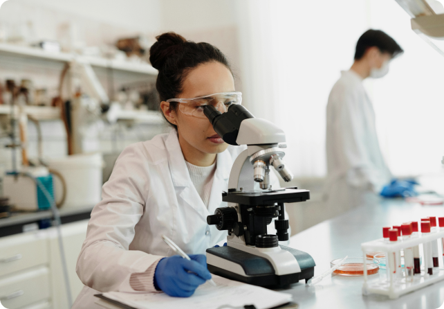 A lady looking into a microscope in a lab