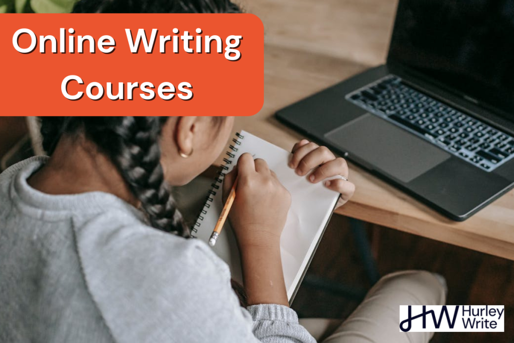 A person writing on a notebook in front of a laptop