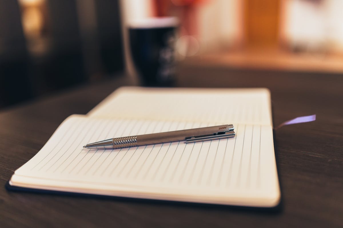 A notebook sitting on a desk with a pen on top of it