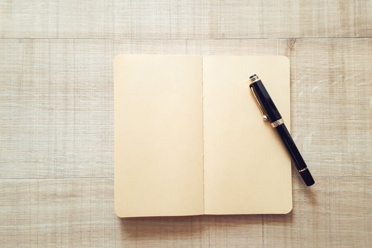 A notebook with a pen sitting on top of it