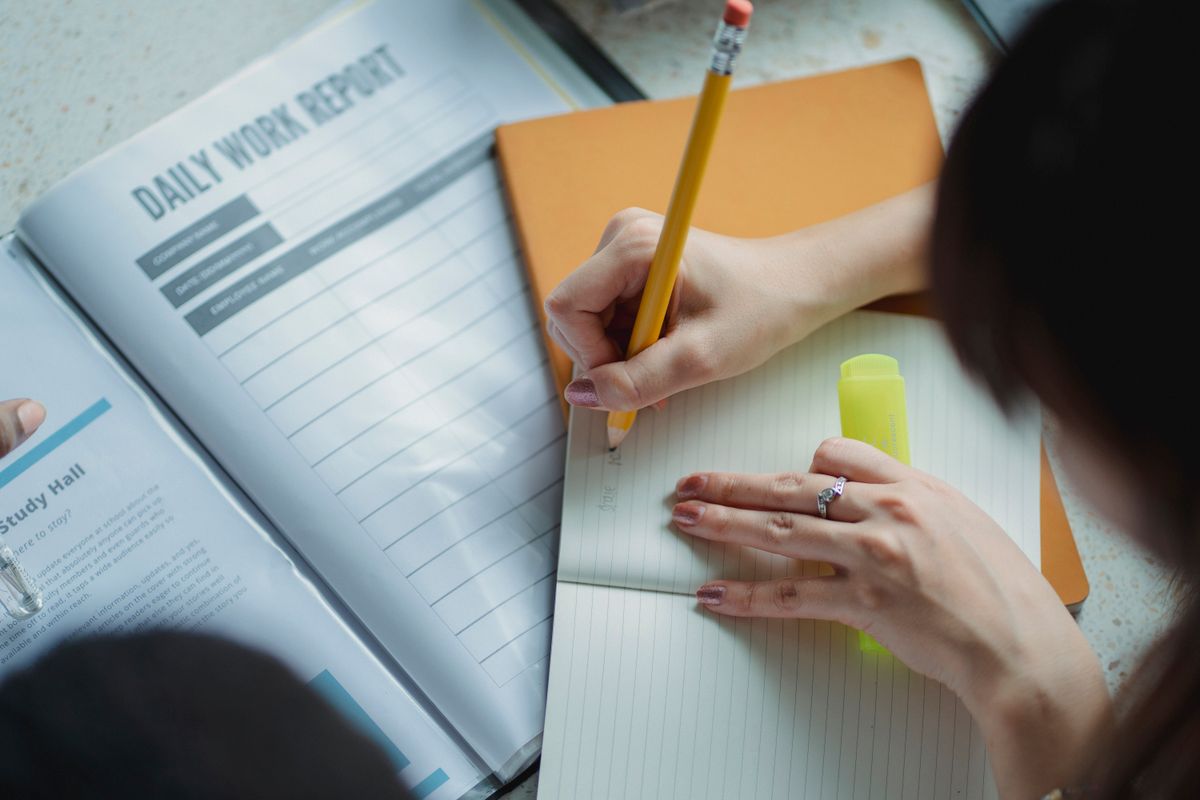 A person writing in a notebook on her desk