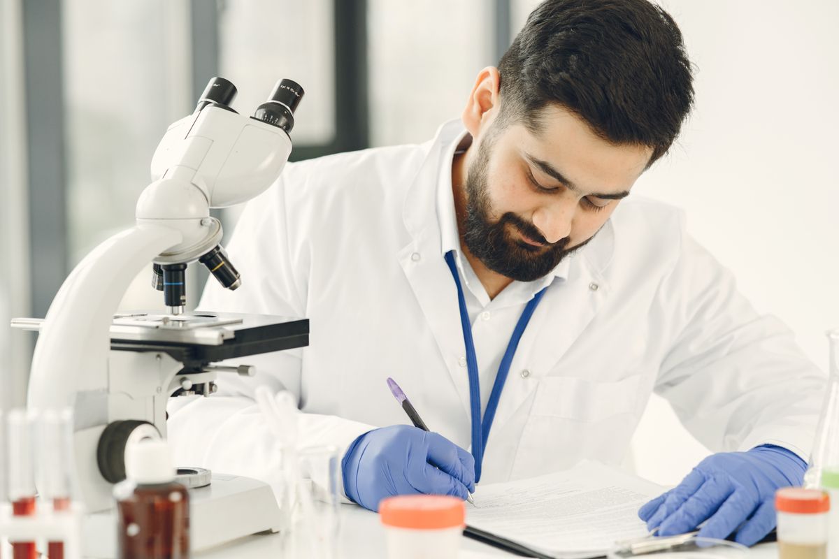A scientist writing something down in a notebook